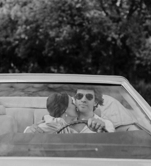 pexels-photo-8629742-8629742 Black-and-white photo of a couple sharing a romantic moment in a classic convertible car.